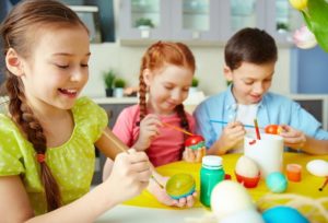 children painting eggs for Easter with healthy teeth