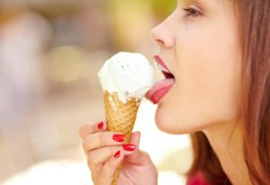 Close-up of a pretty girl enjoying an ice-cream cone even with sensitive teeth