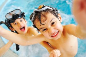 two boys playing in a pool with a big, healthy smile