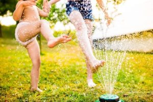 girls trying to stay cool in the sprinkler