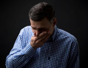 man grimacing in pain from a broken tooth