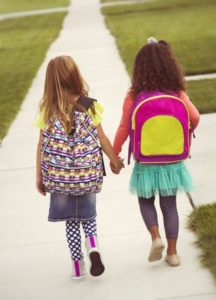 back-to-school photo of girls walking to school with backpacks