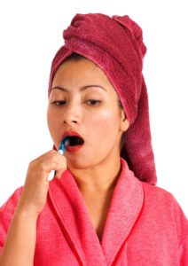 Woman In Bathrobe And Towel Brushing Her Teeth correctly